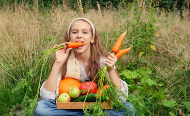 12 year old girl with fresh carrots and  vegetables is sitting on the grass