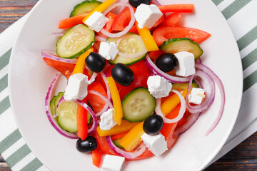 greek salad with tomatoes, cucumbers, olives, pepper and soft feta cheese in a  plate