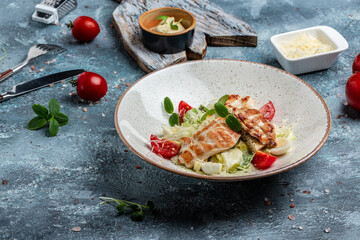 Traditional caesar salad in bowl with Grilled Chicken, leaves, sauce and parmesan. Restaurant menu, dieting, cookbook recipe. top view