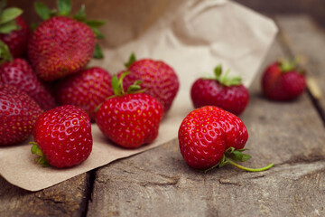 Strawberries on a wooden background with close up. Delicious red berries on the papperwith dark food photo. Juicy and fresh strawberry in summer time shopping.