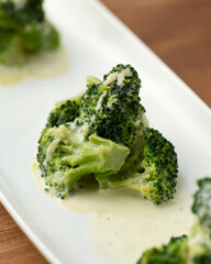 Close up of Blanched broccoli with sauce. Green Vegetables on white plate. Diet food, minimum calories. Soft focus.