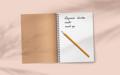 Open realistic notebook with pencil on abstract soft delicate beige background falling shadow overlay from plant.