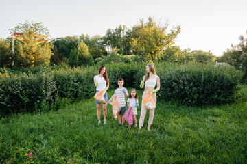 Obraz premium A group of girls with children at sunset are engaged in garbage collection in the park. Environmental care, recycling.