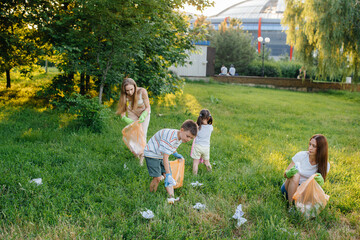 A group of girls with children at sunset are engaged in garbage collection in the park....