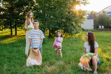 A group of girls with children at sunset are engaged in garbage collection in the park....