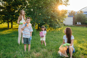 A group of girls with children at sunset are engaged in garbage collection in the park....