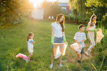 A group of girls with children at sunset are engaged in garbage collection in the park....