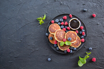 A healthy breakfast of cheese pancakes, berries, and honey. Creative atmospheric decoration