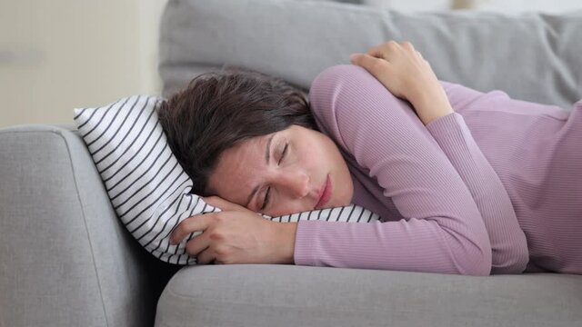 Tired millennial woman try to sleep on sofa. Exhausted caucasian female sleepless need rest on comfortable couch at home. Anxious young adult housewife lying depressed and irritated after work alone