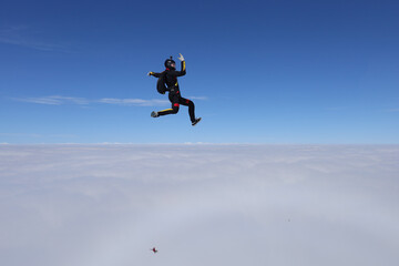 Naklejka na ściany i meble Skydiving. Freefly jump. Solo skydiver is above clouds.
