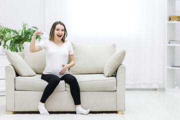 Obraz premium Pregnant woman touching her stomach and holding white socks.