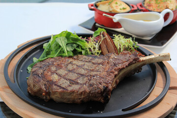 Grilled tomahawk steak on the bone on a ceramic plate horizontal