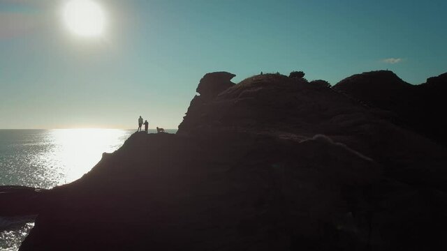 Couple on standing on a coastal clifftop taking a photo, Piha, New Zealand