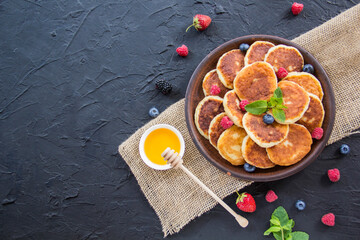A healthy breakfast of cheese pancakes, berries, and honey. Creative atmospheric decoration