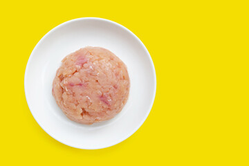 Minced meat of chicken fillet in white plate on yellow background.