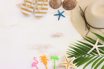 nautical concept with palm leaf, beach hat and starfish over white wooden background