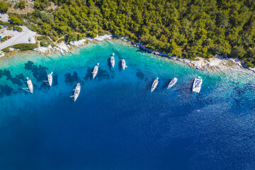 Fototapeta na wymiar Sailing boats at anchor in blue bay of Fiskardo, Kefalonia island, Ionian, Greece. Aerial drone photo