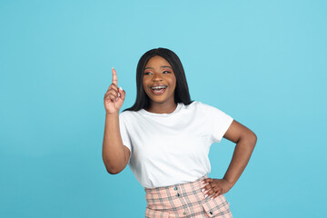 Happy African young woman isolated on blue studio background. Concept of human emotions, facial expression, youth, sales, ad.