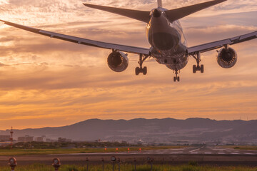 美しい夕焼けにランディングする飛行機の後ろ姿