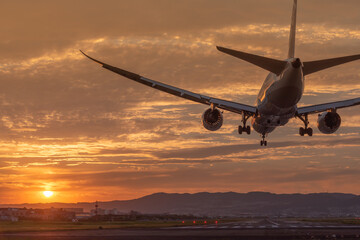 美しい夕焼けにランディングする飛行機の後ろ姿