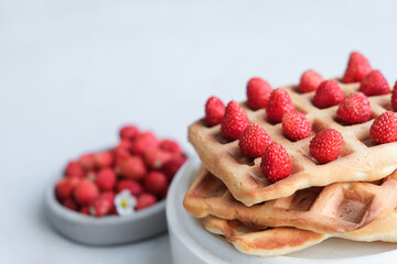 Belgian or Viennese waffles with strawberries on minimalistic concrete grey background. delicious sweet dish