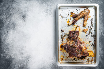Roasted lamb mutton whole leg in a baking dish. White background. Top view. Copy space