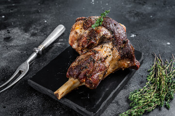 Oven Roasted lamb mutton whole leg with thyme. Black background. Top view