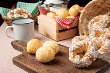 Brazil cheese bread and sweet biscuit and a cup of coffee on a table with beige tablecloth, selective focus.