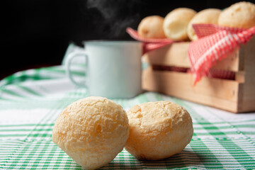 Brazil Cheese Bread, box with cheese buns and a cup on a green checkered tablecloth, selective focus.