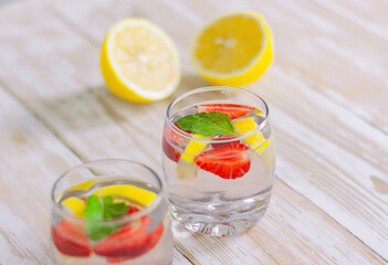 summer cocktail of citrus and berries. refreshing lemonade of strawberries, lemon and mint in two glasses on a light background.