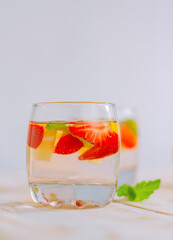 strawberry-citrus homemade summer refreshing drink. lemon water with berries in a glass on the table.
