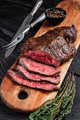 Grilled Butchers choice steak Onglet Hanging Tender beef meat on a cutting board. Black wooden...