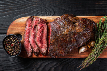 Grilled Butchers choice steak Onglet Hanging Tender beef meat on a cutting board. Black wooden...