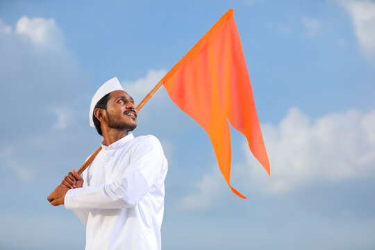 Young indian man (pilgrim) in traditional wear and waving religious flag.