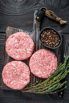 Raw Chicken Turkey Patty, Ground Meat Cutlets On A Chopping Board. Black Wooden Background. Top View