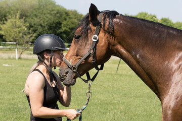 Portrait of a girl  in helmet kissing a sorrel horse The girl in the helmet kisses the horse,...