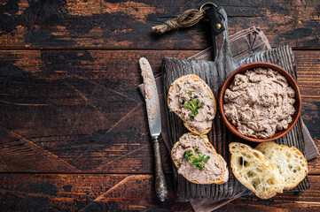 Toasts with Duck pate Rillettes de Canard on wooden board. Dark wooden background. Top View.  Copy...