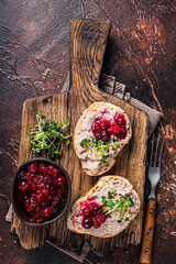 Duck rillettes pate toasts with sprouts on a wooden board. Dark background. Top View