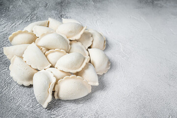 Fototapeta na wymiar Raw frozen dumplings pierogi on a kitchen table. White background. Top View. Copy space