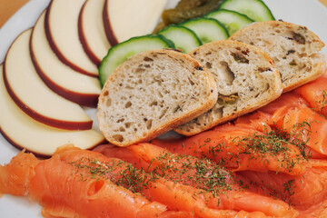 Plate with smoked salmon, slicec bread, fresh cucumbers and cheese. Serving of appetizer. Seafood, bakery product