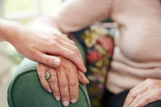 Close Up Of Hands With Young Woman Comforting Senior Female