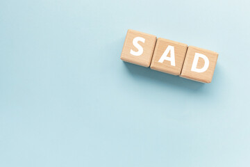 Text ETF on wooden cubes on blue background. Abbreviation of 'Seasonal affective disorder'. Square wood blocks. Top view, flat lay. 