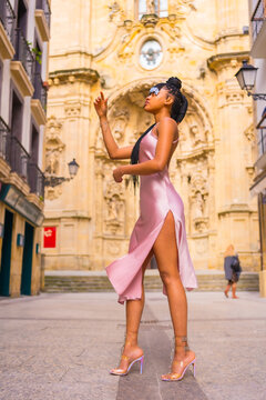 Beautiful Dominican ethnic girl with braids with a beautiful pink dress. Fashion enjoying summer in a beautiful city church, vertical photo