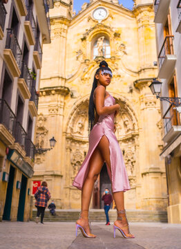 Dominican ethnic girl with braids with a beautiful pink dress. Fashion enjoying the summer in a beautiful church of the city, seductive look