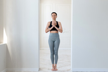 A young woman practices yoga, prays and comprehends Zen in the arch of a bright room. The concept...