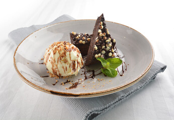 walnut chocolate brownie with vanilla ice cream and peanut, chocolate sauce, mint leaf dessert on round plate western pastry halal menu