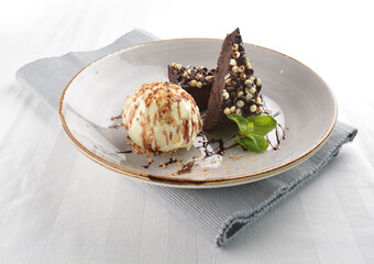 walnut chocolate brownie with vanilla ice cream and peanut, chocolate sauce, mint leaf dessert on round plate western pastry halal menu