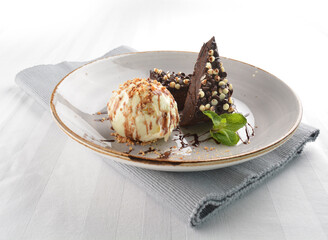 walnut chocolate brownie with vanilla ice cream and peanut, chocolate sauce, mint leaf dessert on round plate western pastry halal menu