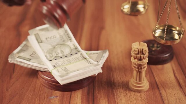 Concept showing of judicial corruption by hitting judge gavel on currency note bundles.