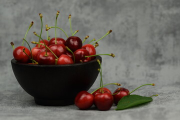 Sweet cherries in bowl on grey background.